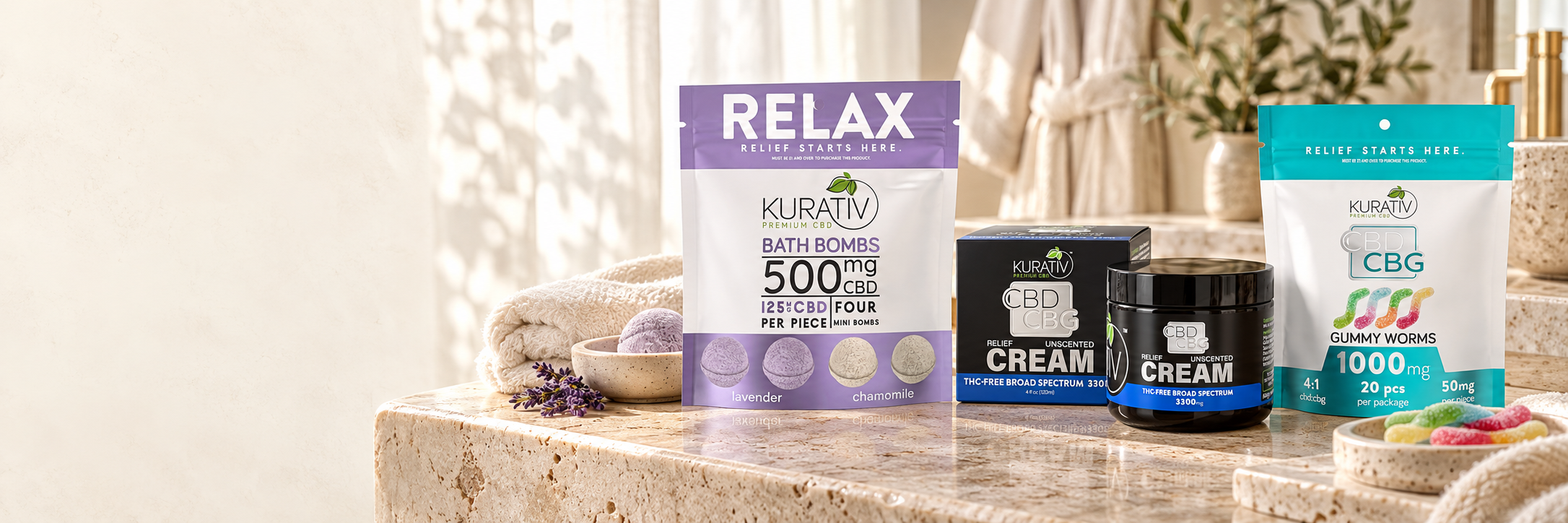 Kurativ Premium CBD bath bombs, broad-spectrum CBD CBG cream and THC-free CBG gummy worms on a light stone vanity